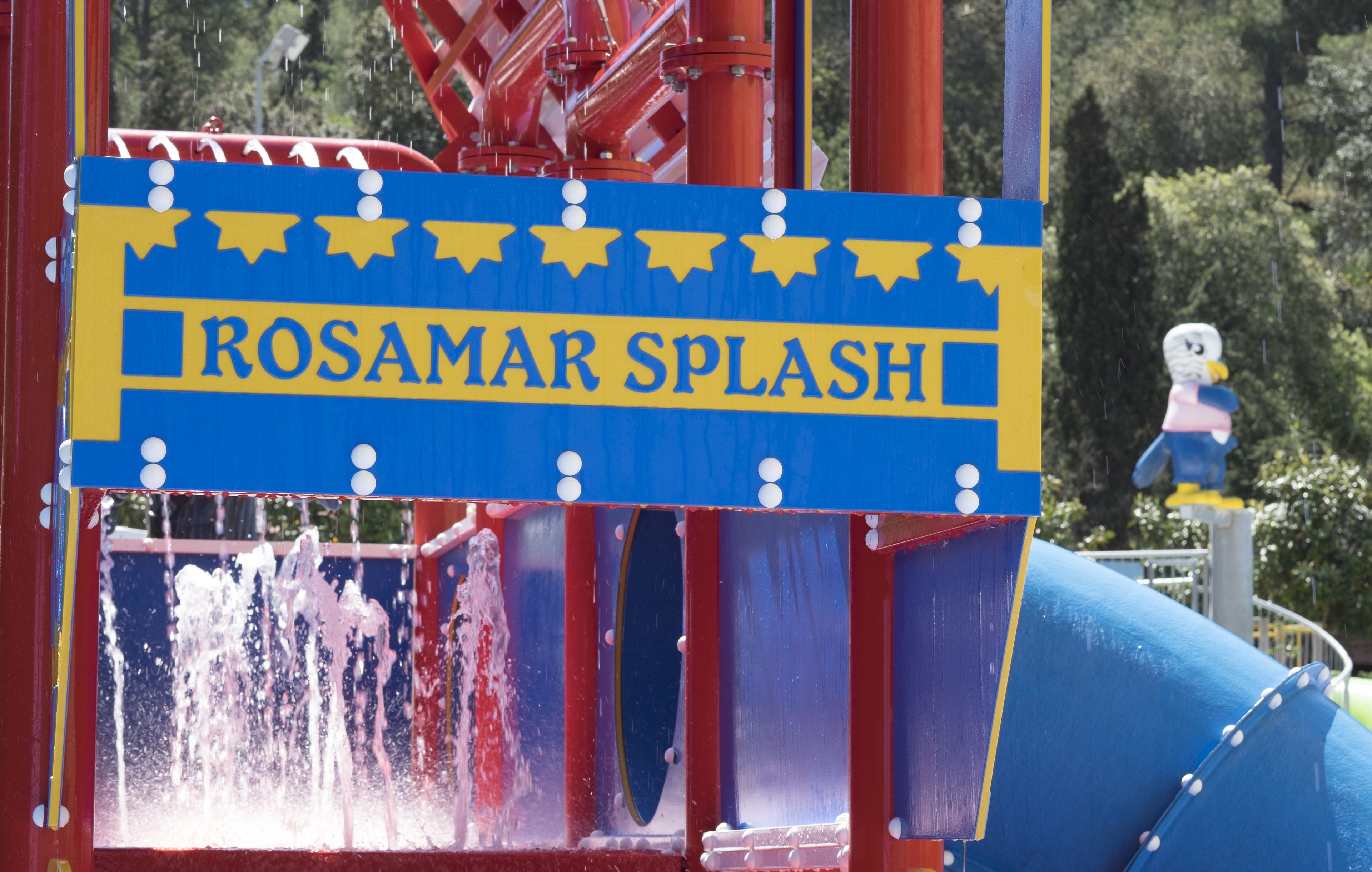 A water play area with a sign reading "Rosamar Splash" and a figure of a bird on a pole.