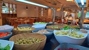 Un bufé con diversas opciones de comida, como maíz, aceitunas y pasta.