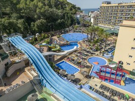 Un parque acuático con múltiples toboganes y piscinas, rodeado de palmeras y edificios de hotel.