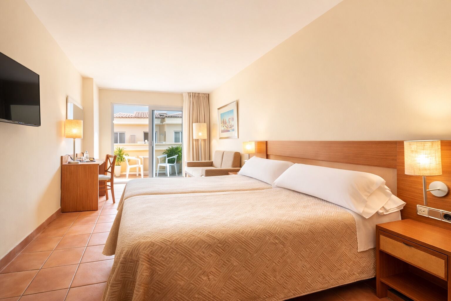 Une chambre d’hôtel avec deux lits, un bureau, une télévision et un balcon avec vue.