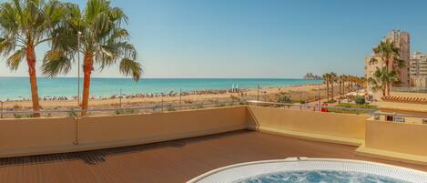 A rooftop pool with a view of the beach and palm trees.