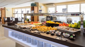 Un buffet proposant une variété de plats, notamment des fruits, des pâtisseries et des desserts, disposés sur un comptoir avec des assiettes et des ustensiles de service.