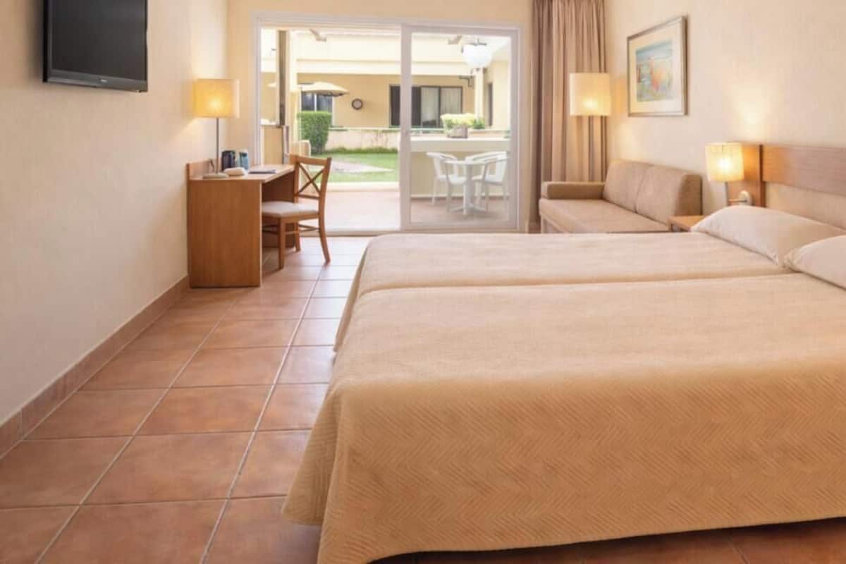 Ein Hotelzimmer mit zwei Betten, einem Schreibtisch und einem Stuhl.