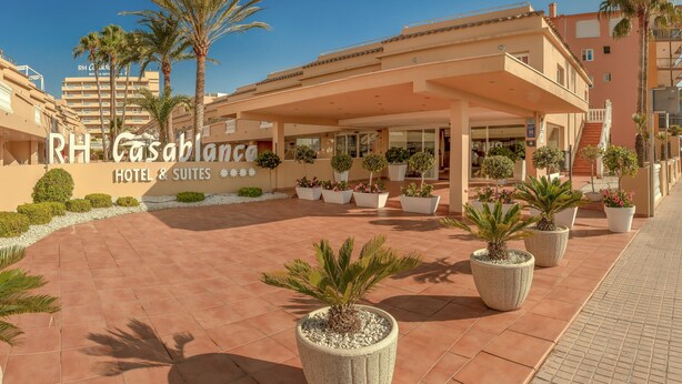 L’entrée d’un hôtel, avec un patio abrité, des palmiers et des plantes en pot.