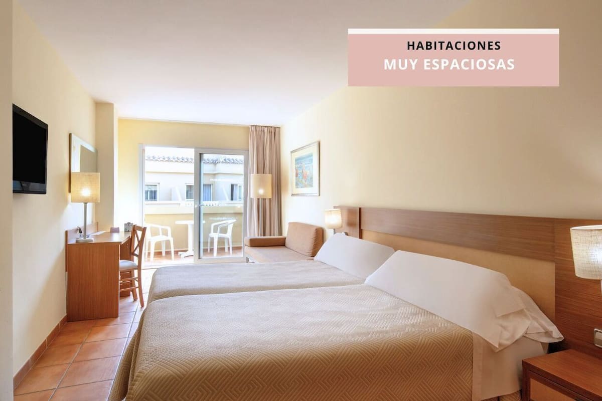 Ein geräumiges Hotelzimmer mit zwei Betten, einem Schreibtisch und einem Stuhl.