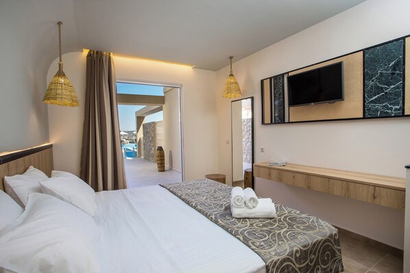 A hotel room with a bed, a TV, a bathroom vanity, and a view of a pool and outdoor area.