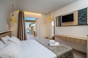Habitación de hotel con cama, televisión, tocador de baño y vistas a una piscina y zona exterior.