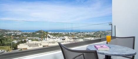 Un balcón con mesa y sillas, con vistas a un pueblo costero.