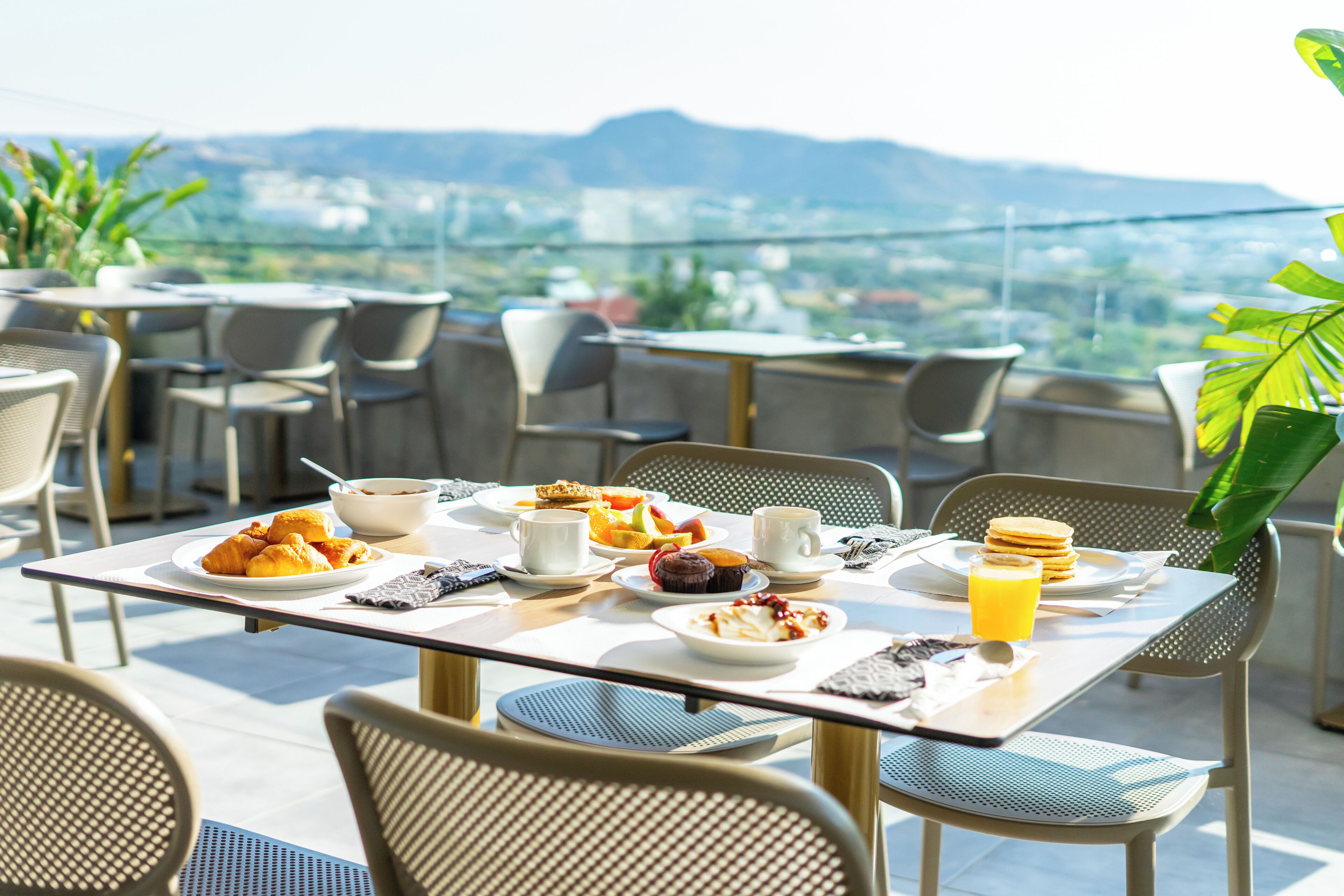 Une table à manger avec des aliments pour le petit-déjeuner et une vue sur la ville.