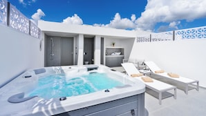 Un'area spa moderna all'aperto con vasca idromassaggio, poltrone relax e un angolo cottura.