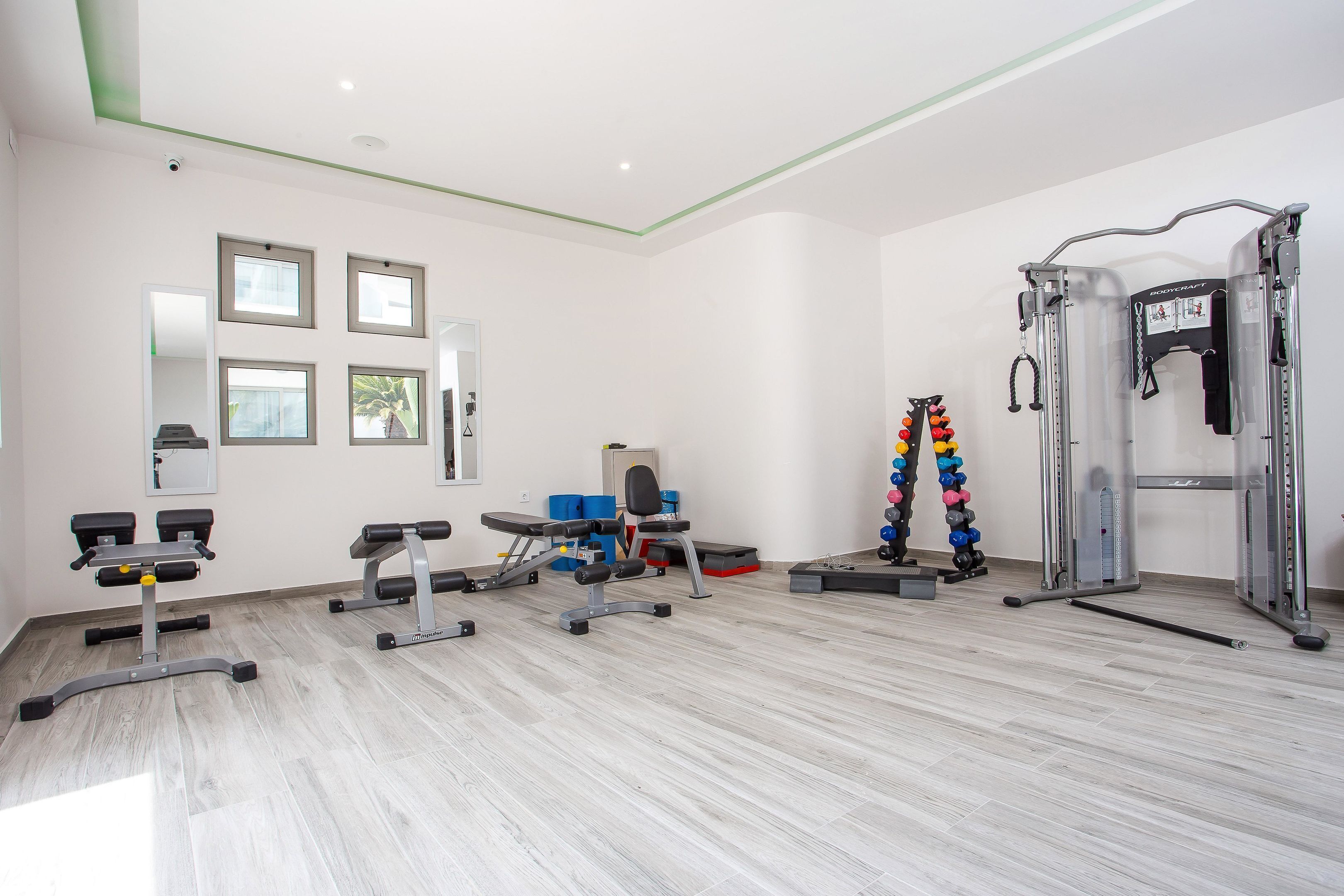 Une salle de sport équipée de matériel d’exercice, de miroirs et dotée d’un plafond blanc.