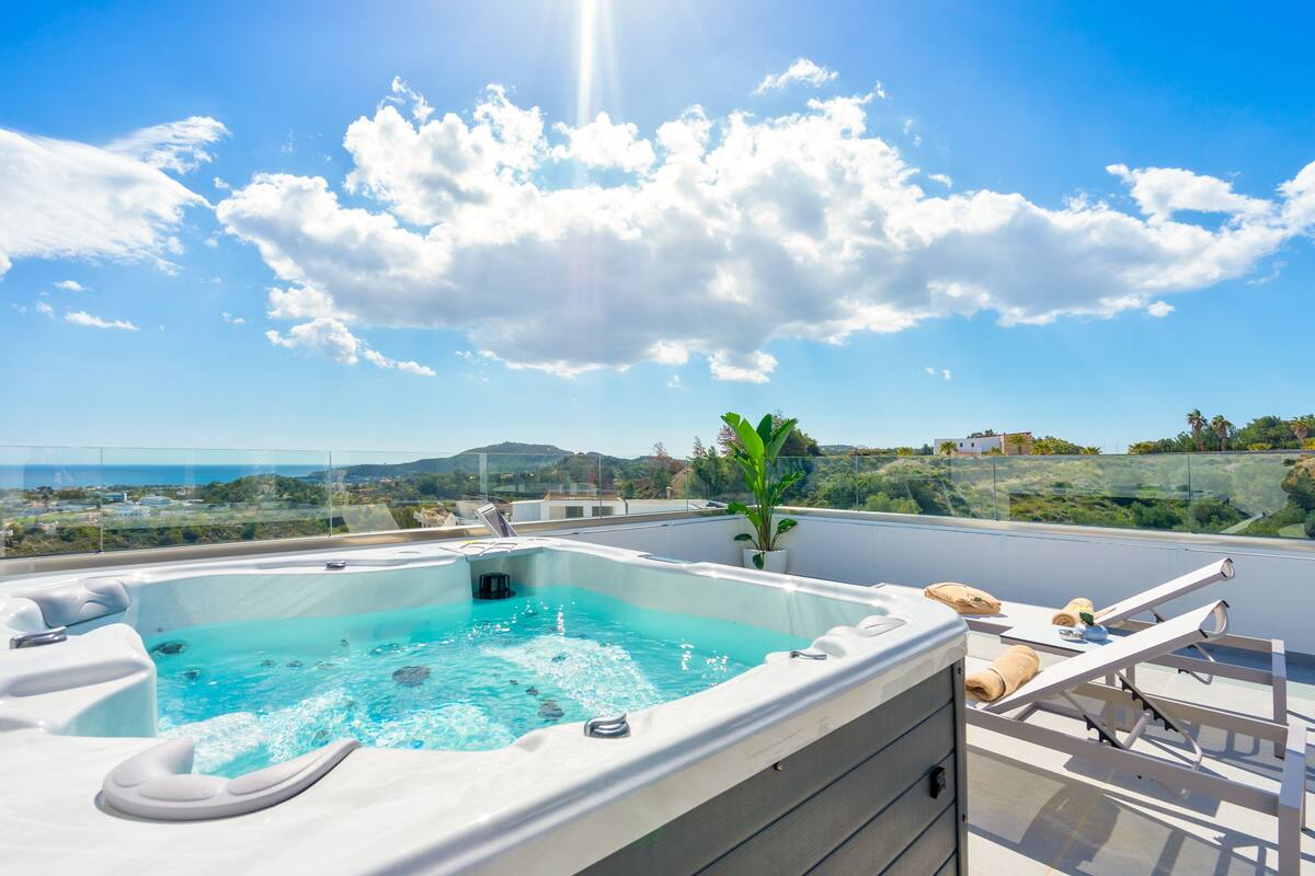 A rooftop hot tub with a clear view of the surrounding landscape, including hills and a distant cityscape.