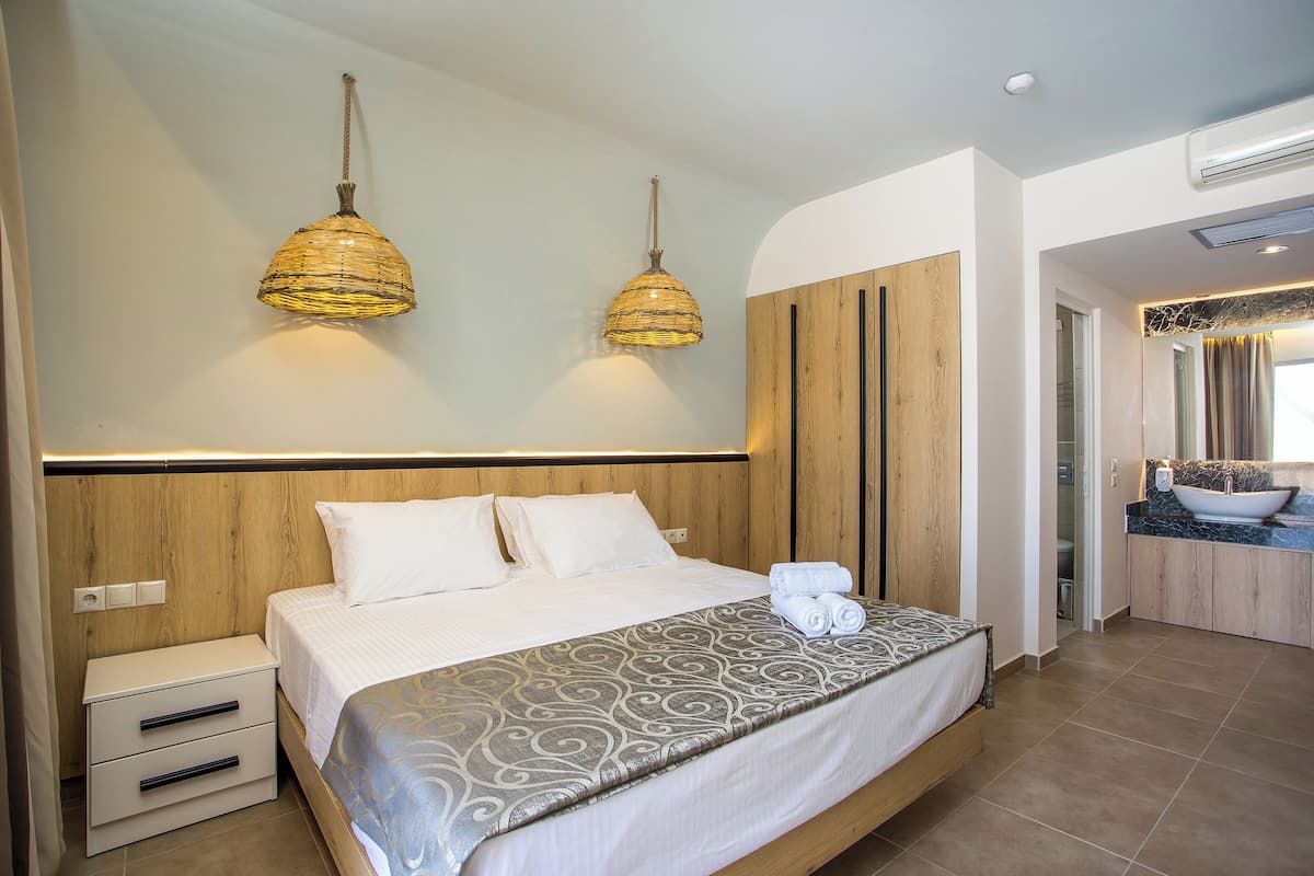 A modern bedroom with a large bed, bedside tables, and a bathroom with a sink and mirror.