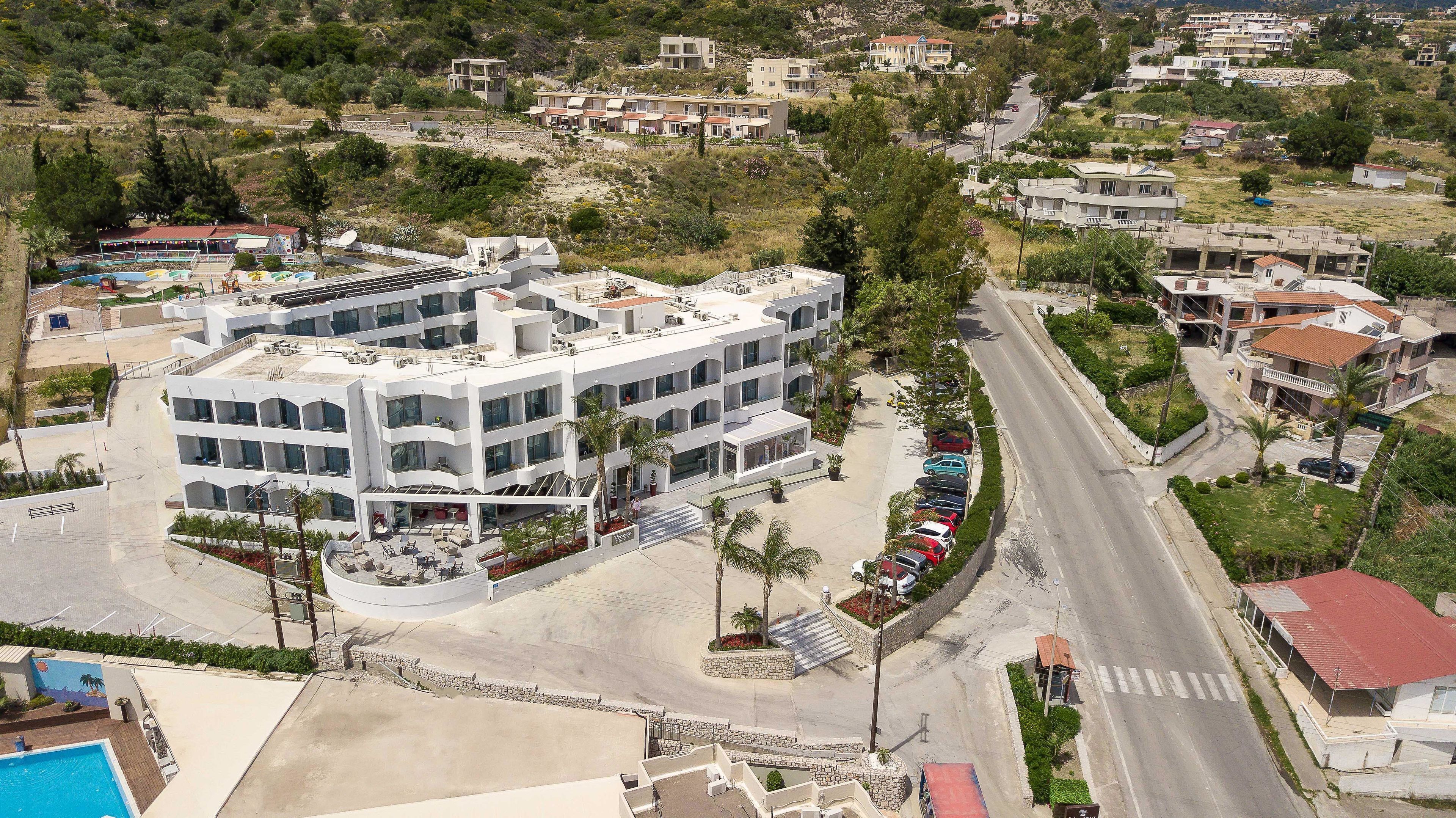 A modern multi-story hotel with a pool, parking, and a view of the surrounding area.