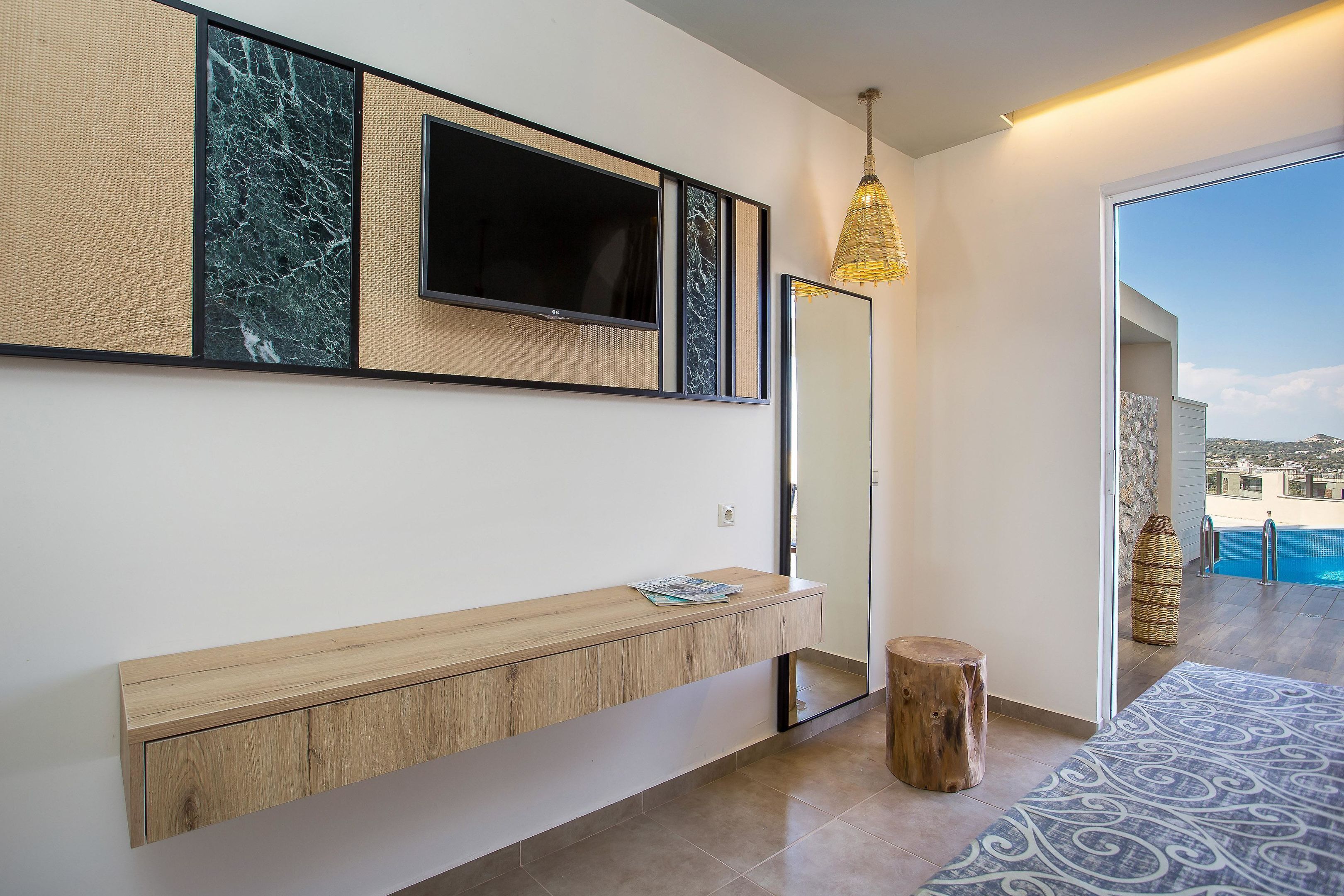 A modern interior with a wooden console table, a flat-screen TV, a mirror, and a view of a pool.