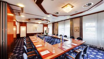 A conference room with a long table, chairs, and a patterned carpet.