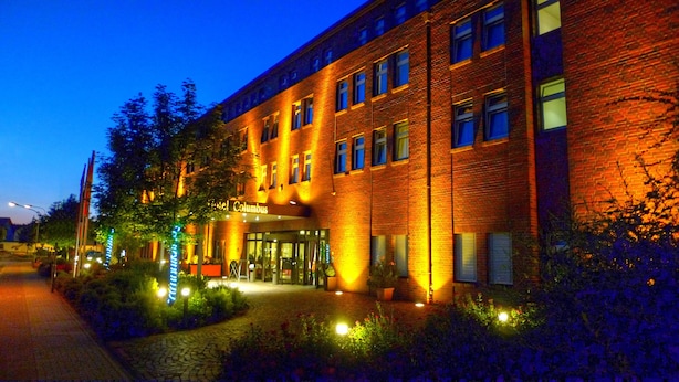 A hotel with a brick facade, illuminated windows, and a sign reading "Hotel Columbus." - Trans World Hotel Columbus (Seligenstadt)
