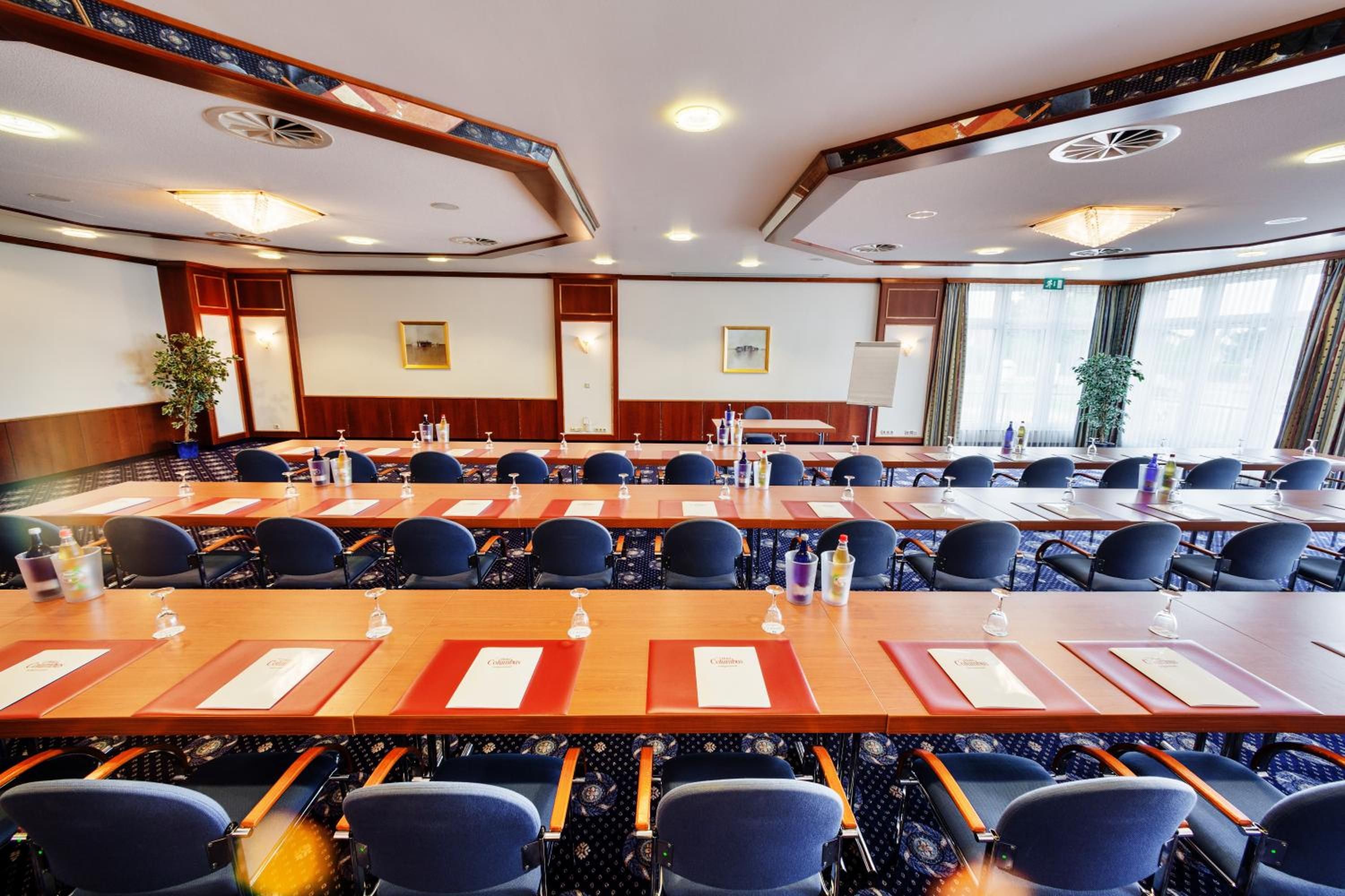 A conference room with multiple tables and chairs, equipped with nameplates and water bottles.