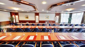 A conference room with multiple tables and chairs, equipped with nameplates and water bottles.