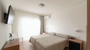 A hotel room with two beds, a desk, a TV, a mini-fridge, and a window with curtains. - Hotel RH Riviera -  Recommended for Adults By Hoteles RH (Gandia)