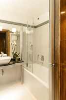 Un bagno moderno con cabina doccia in vetro, lavabo bianco e porta in legno.