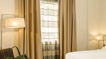 Habitación de hotel con cama, sofá, mesa con bandeja de desayuno, lámpara y cortinas.