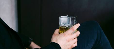 A person sitting on a leather couch holding a glass of beer.