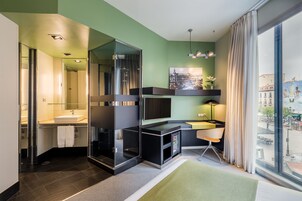 A modern bathroom with a glass shower enclosure, a sink, and a desk with a chair.