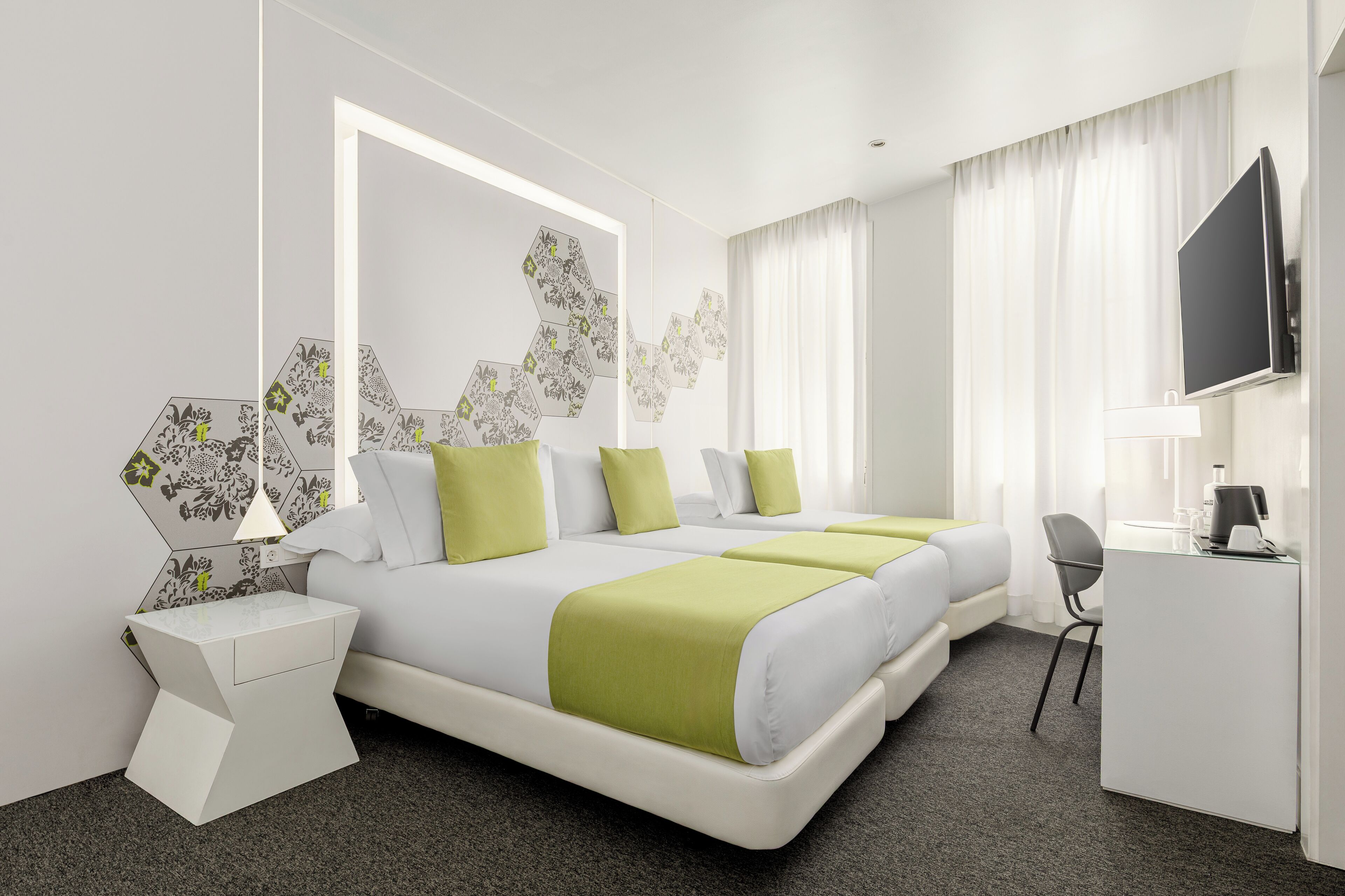 A modern hotel room with a large bed, a desk, and a TV.