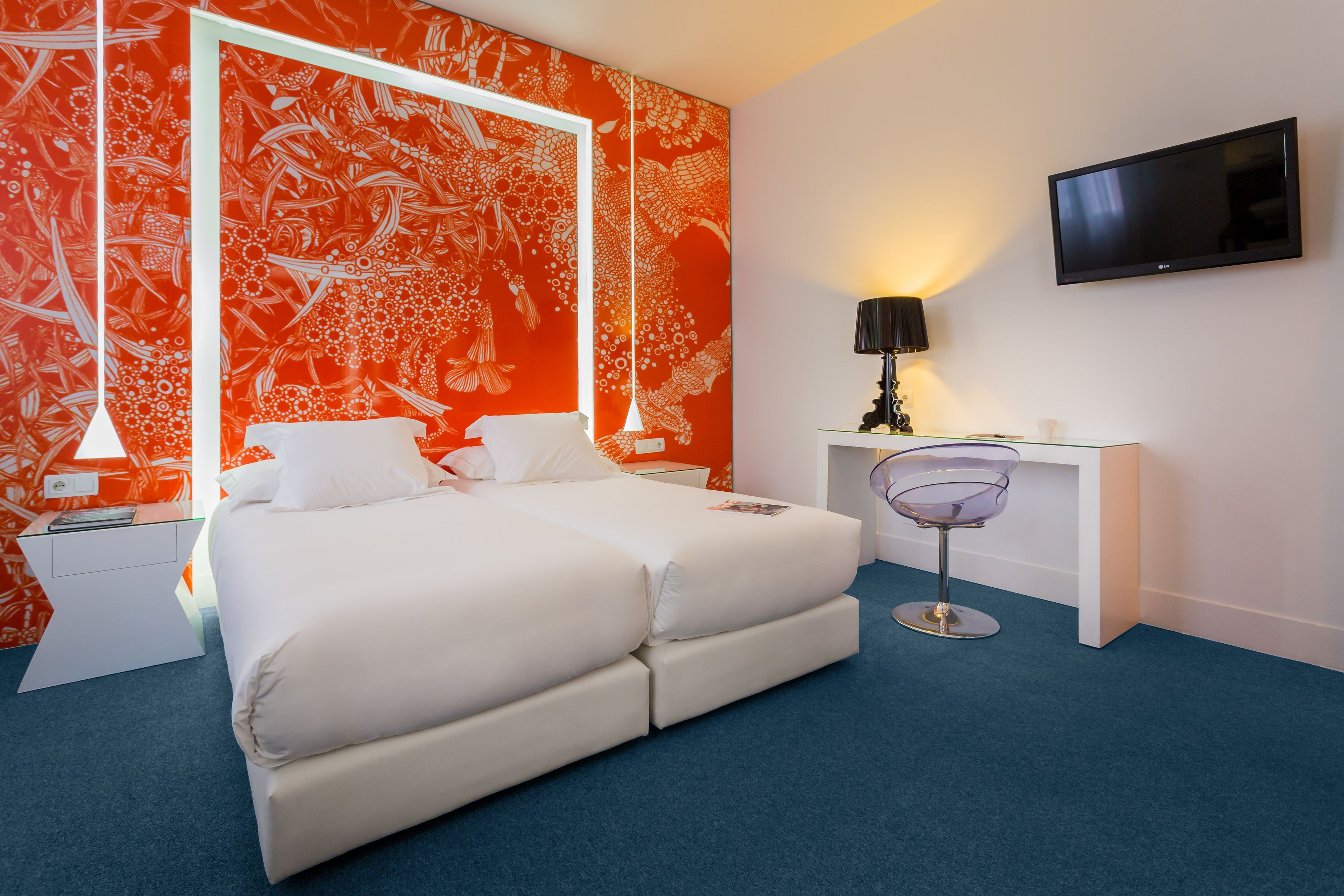 A modern hotel room with a large bed, a desk, and a TV.
