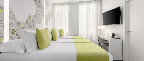 Habitación de hotel con una cama grande, un escritorio, una silla, un televisor y una ventana con cortinas.