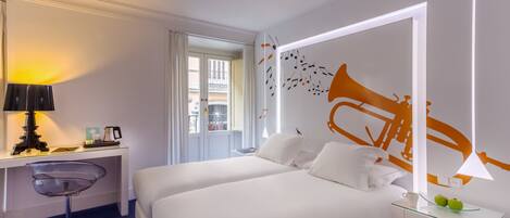 A hotel room with a bed, a desk, a chair, and a large mirror with a wall decoration.