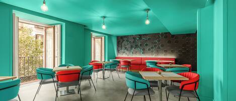 A modern restaurant with teal walls, red seating, and hexagonal patterned wall.