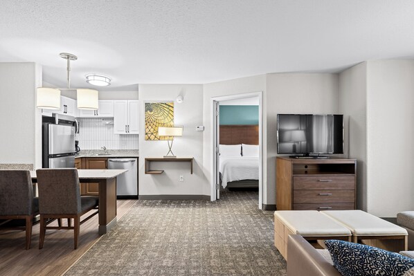 Een compacte hotelkamer met een kitchenette, een bed, een televisie en een zithoek.