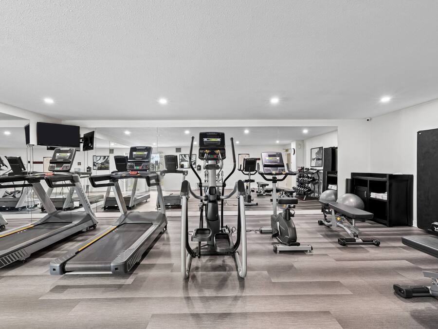 Une salle de sport équipée de tapis de course, de vélos elliptiques et de matériel de musculation.