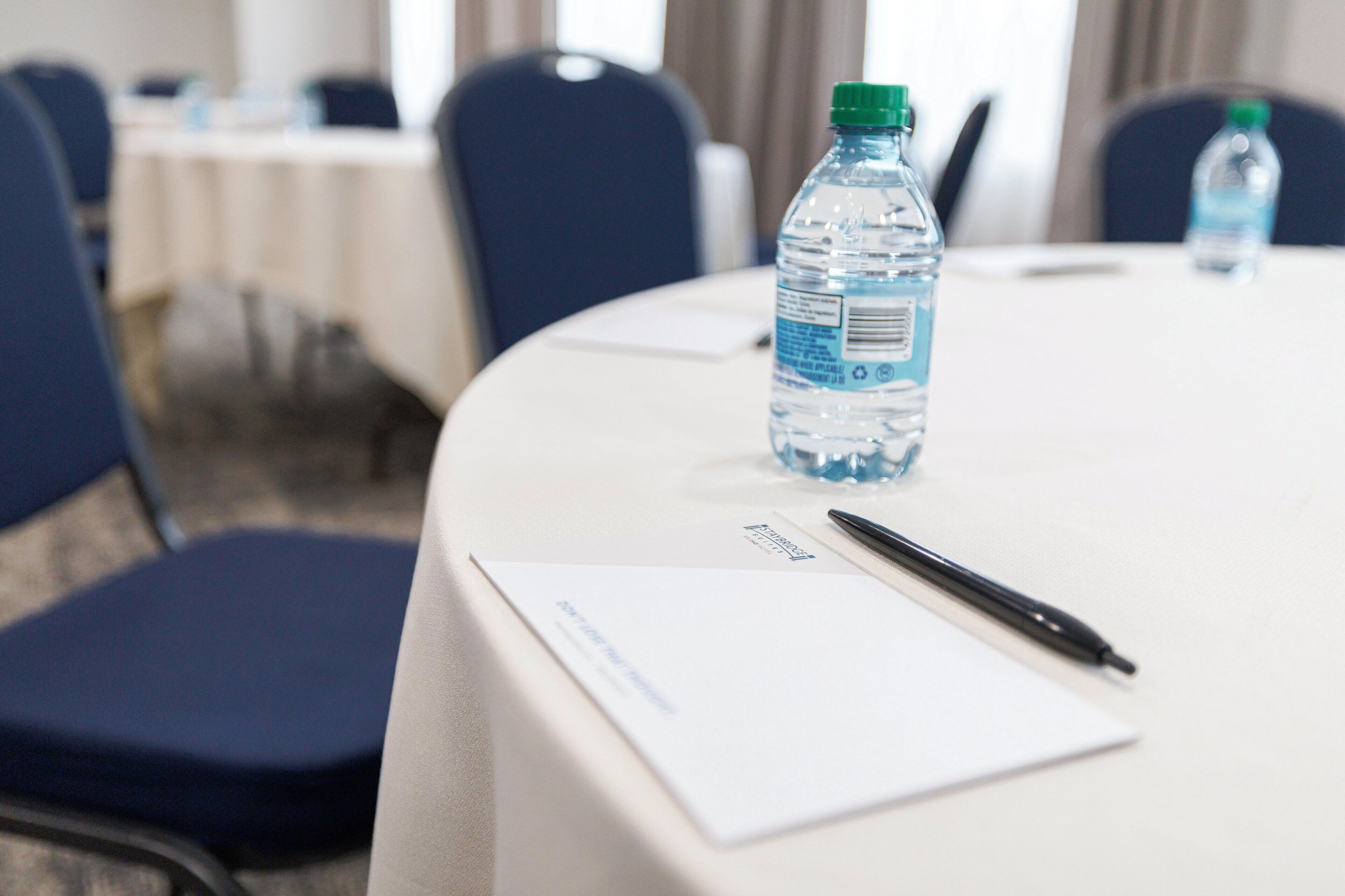 Una mesa de conferencias con una botella de agua, un bolígrafo y un bloc de notas.