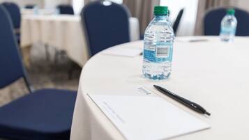 Una mesa de conferencias con una botella de agua, un bolígrafo y un bloc de notas.