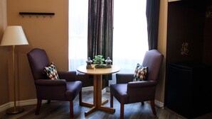 Una habitación con dos sillones, una pequeña mesa redonda, una lámpara de pie y una chimenea.