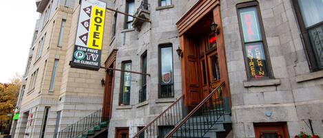 A hotel with a sign indicating it is a 2-star establishment, a staircase leading to the entrance, and a visible entrance door.