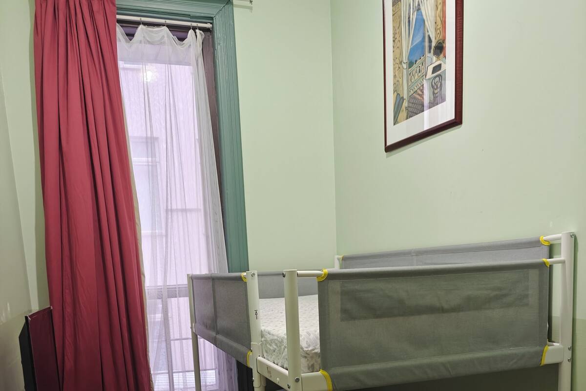 A bunk bed room with a window, a painting on the wall, and a trash bin.
