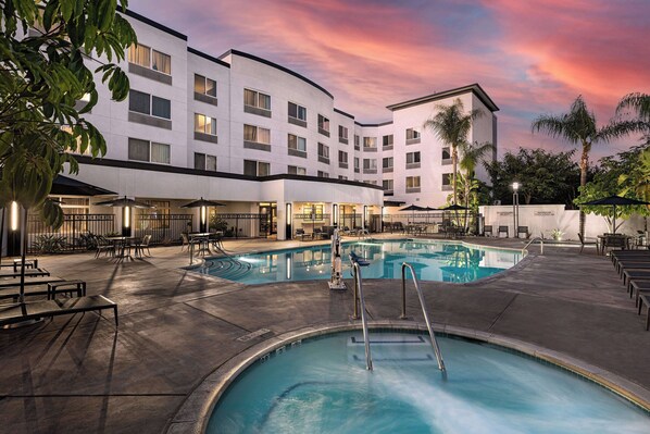 Un hôtel doté d’une piscine, d’un espace extérieur aménagé et offrant une vue sur le coucher de soleil.