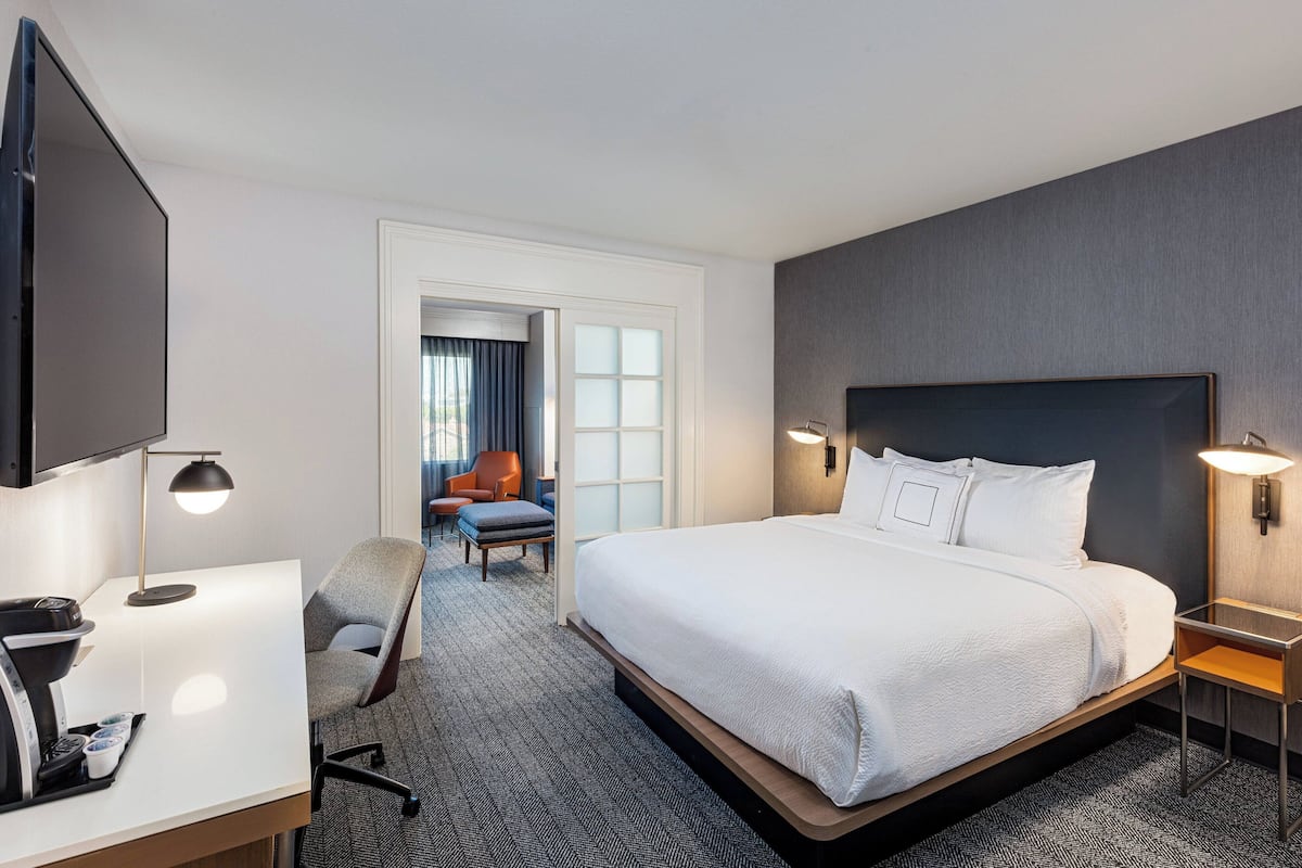 A hotel room with a large bed, a desk with a computer, a chair, and a TV.