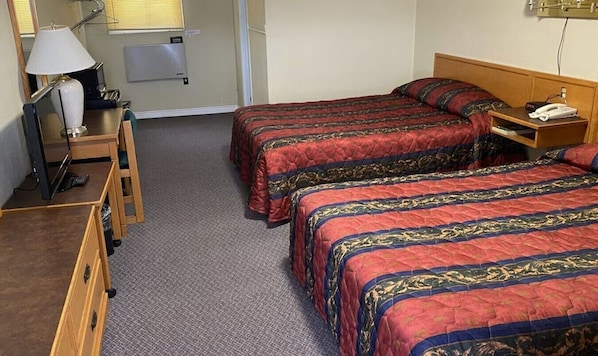 Une chambre d’hôtel avec deux lits, un bureau avec une lampe, une chaise et un téléphone.