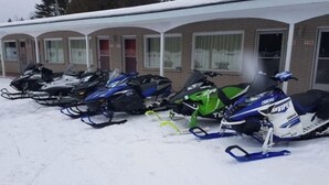 A row of snowmobiles parked in front of a motel with a brick facade and arched windows. - Skyways Motel Muskoka Gravenhurst ON 11 (Gravenhurst)