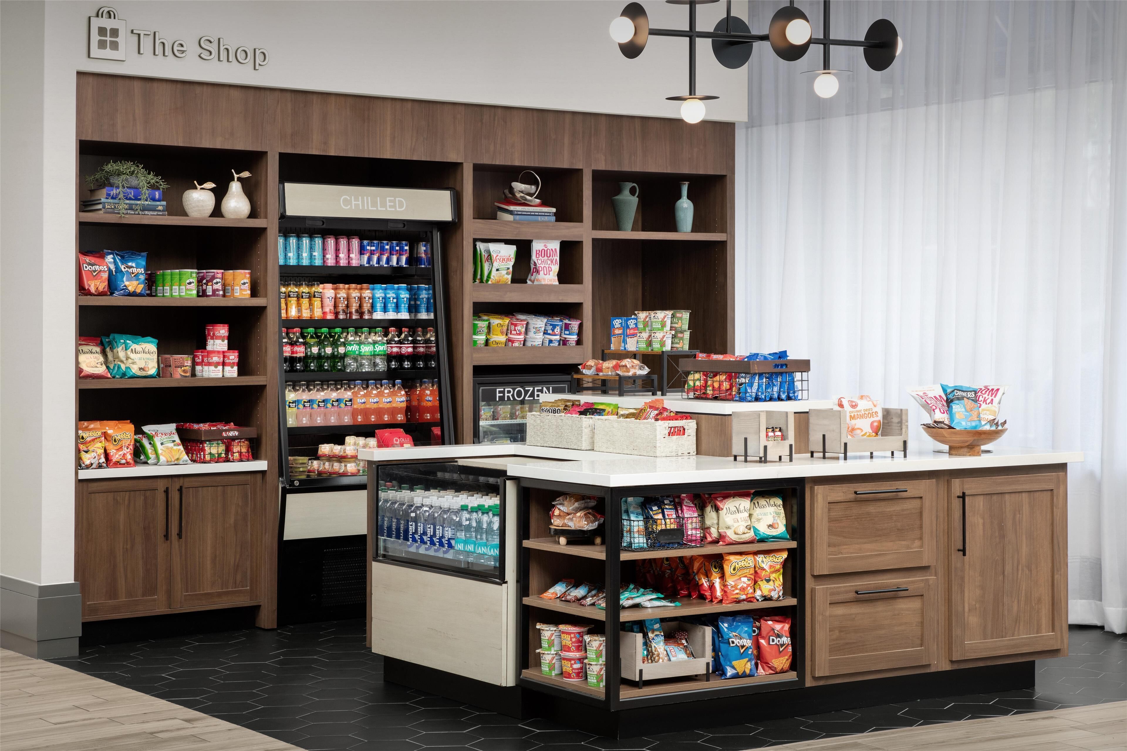 A grocery store interior with shelves stocked with snacks, beverages, and frozen goods.