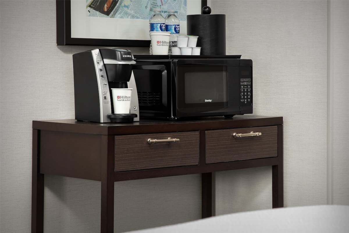 Eine Minibar mit Kaffeemaschine, Mikrowelle und Wasserflaschen.