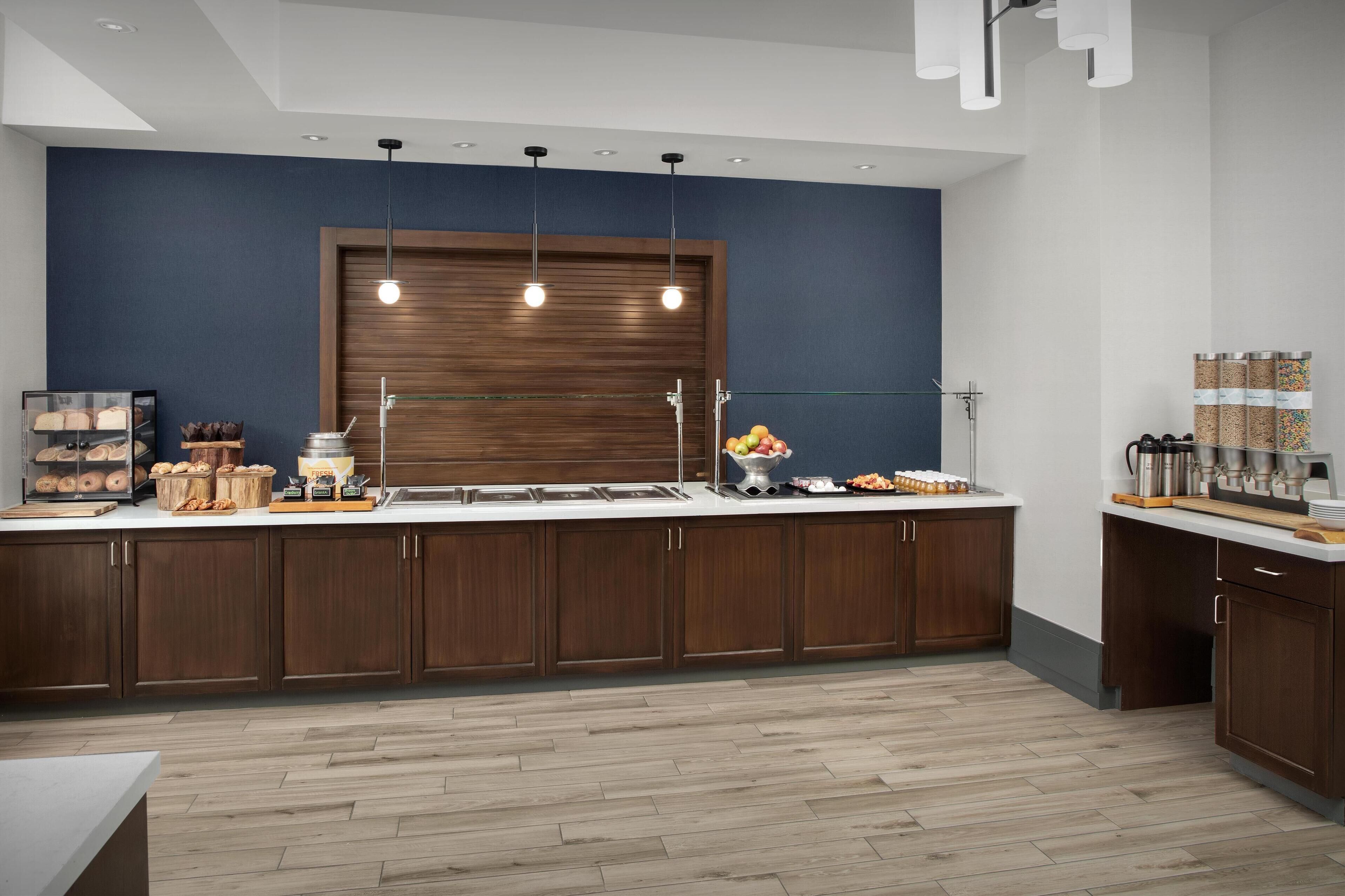 Cocina moderna con armarios de madera, encimera de mármol e iluminación colgante.