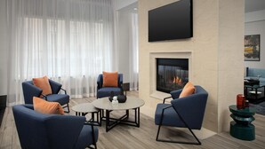 A modern living room with a fireplace, comfortable seating, and a flat-screen TV. - Hilton Garden Inn Portsmouth Downtown (Portsmouth)