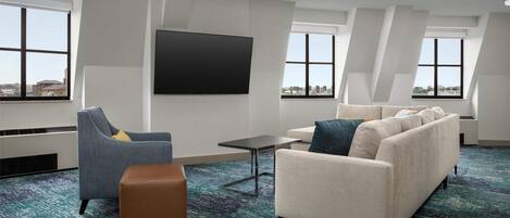 Una habitación de hotel moderna con un televisor de pantalla plana grande, un sofá, una silla y una mesita.