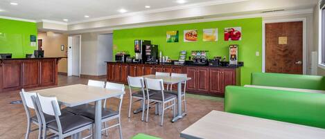 A modern restaurant with green walls, wooden cabinets, and a variety of seating options including tables and booths.